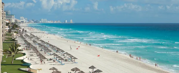 High-angle view of a pristine Cancún beach with clear turquoise waters, lush greenery, and vibrant surroundings. Things to do in Cancún.