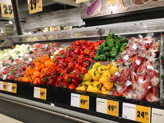 Fresh vegetables neatly arranged in a grocery store, featuring tomatoes, peppers, and greens on wooden shelves under warm lighting. Perfect choice for shoppers seeking fresh produce in a vibrant market setting.